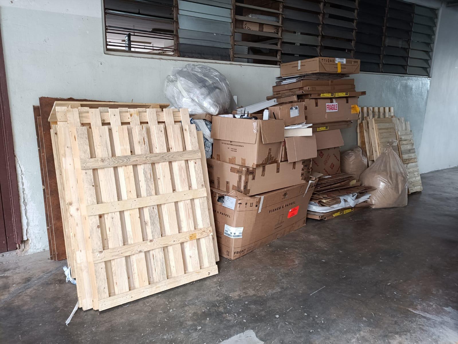 Stacked wooden pallets and cardboard boxes accumulated in a commercial space awaiting removal.